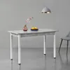 A dining table with a concrete look top and white legs, set in a minimalist room with a gray wall and floor. A vase with flowers and a plate of lemons are on the table. A gray chair is partially visible on the right. Anteprima dell’immagine prodotto