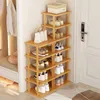 A multi-tier wooden shoe rack filled with various shoes and a handbag, placed near a doorway and a bench with clothes hanging on a rack beside it. Produktbild-Vorschau