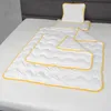 A baby pillow and blanket set laid out on a bed. Produktbild-Vorschau