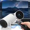 A hand is holding a remote control in front of a projector, with a large screen displaying a starry night sky and mountains in the background. Produktbild-Vorschau