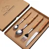 A set of four stainless steel cutlery pieces with wooden handles, neatly arranged in a cardboard gift box. Voir les images du produit