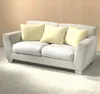 A light-colored sofa with three yellow pillows against a tan wall. Podgląd zdjęcia produktu