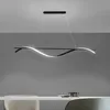 A modern, wavy LED pendant light hangs above a dining table. Produktbild-Vorschau
