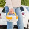 A person holding a white and yellow electric lunch box in front of a white car. Produktbild-Vorschau