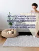 A woman is sitting on a couch next to a dog bed with a French bulldog in it. A rug is on the floor in front of the dog bed. Text overlays describe the product's features. Produktbild-Vorschau