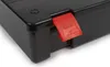 A close-up shot of the corner of a black storage box with a red latch. Produktbild-Vorschau