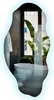 A modern bathroom with a freestanding bathtub and a large window overlooking a city building, with a large tropical plant in the foreground. Produktbild-Vorschau