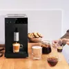 A coffee machine is shown making coffee, with cookies and other drinks on a wooden table, and a person's hands reaching for a cup. Produktbild-Vorschau