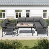 An outdoor patio set with a sectional sofa, chairs, and a coffee table, set against a white house with windows. Podgląd zdjęcia produktu