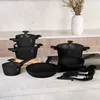 A collection of black cookware set on a kitchen counter with a vase of dried flowers in the background. Náhled obrázku produktu