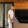 A man is putting a cushion into a wicker storage box on a wooden deck. Produktbild-Vorschau