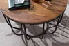 A close-up view of a round wooden coffee table with a black metal frame, resting on a textured rug. Voir les images du produit