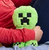 A person is holding a green plush toy with a pixelated face. Produktbild-Vorschau