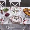 A beautifully set Christmas table with festive dinnerware, food, and a lit candle. Anteprima dell’immagine prodotto