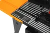 A close-up view of a workbench with an orange extension and a black and silver ribbed surface. There is a label with text and symbols on the surface. Anteprima dell’immagine prodotto