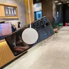 A smartphone with a magnetic charging puck attached is shown in a cafe-like setting. Náhled obrázku produktu