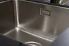 A close-up view of a stainless steel kitchen sink with a drain. Produktbild-Vorschau
