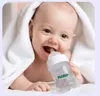 A baby wrapped in a white towel is holding and drinking from a baby bottle. Náhľad obrázku produktu