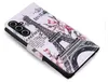 A close-up, angled view of a white flip phone case with a vintage-style illustration of the Eiffel Tower and flowers. Produktbild-Vorschau