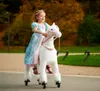 A young girl dressed as a princess rides a white toy horse with wheels in a park during autumn. Anteprima dell’immagine prodotto
