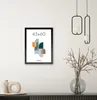 A framed picture with abstract art is displayed on a wall above a dark cabinet. The picture frame is black and contains a graphic with geometric shapes and the text '45x60' and 'ACAZA'. Two modern pendant lights hang from the ceiling above and to the right Produktbild-Vorschau