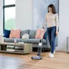 A woman is using a vacuum cleaner in a living room. Voir les images du produit