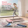 A woman is running on a pink treadmill in a bright room with a view of a city skyline and park. Produktbild-Vorschau