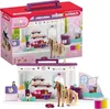A toy playset of a horse grooming salon, shown both in its packaging and set up. Produktbild-Vorschau