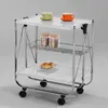 A white and chrome serving trolley with two cups, two jars, and two croissants on it. Produktbild-Vorschau