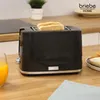 A black toaster with two slices of toast is on a wooden countertop, next to a glass of orange juice. Podgląd zdjęcia produktu