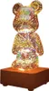 A clear product shot of a teddy bear-shaped night light on a wooden base. Voir les images du produit