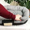 A person's hand is shown pressing down on the edge of a gray pet bed. Anteprima dell’immagine prodotto
