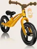 A yellow balance bike is shown against a light beige background. Produktbild-Vorschau