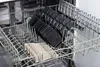 A dishwasher rack holding multiple small black raclette pans and some wooden separators. Produktbild-Vorschau