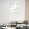 A modern living room with a sectional sofa, coffee table, and a contemporary square LED ceiling light fixture mounted on the wall. Produktbild-Vorschau