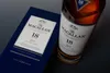 A bottle of Macallan 18 Years Double Cask Scotch Malt Whisky and its blue presentation box are placed on a dark gray surface. Produktbild-Vorschau