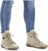 A close-up view of a person's legs wearing blue jeans and beige lace-up boots. Voir les images du produit