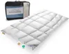 A white quilted comforter is laid out on a white surface, with a black and blue storage bag behind it. Produktbild-Vorschau