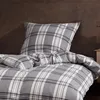 A close-up view of a plaid duvet cover and pillowcase on a bed. Produktbild-Vorschau