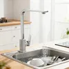 A kitchen sink with a faucet running water into it, with dishes in the sink. Produktbild-Vorschau