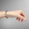 A hand wearing a colorful beaded bracelet against a gray background. Produktbild-Vorschau