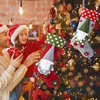 A father and daughter are decorating a Christmas tree, hanging stockings. Náhľad obrázku produktu