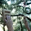 Klettergriff "Rocky" von YY Vertical; montiert an einer Kletterwand; mit zwei Händen; die den Griff halten. Podgląd zdjęcia produktu