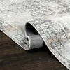 A close-up view of a rolled-up rug on a dark wooden floor. Produktbild-Vorschau