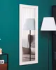 A full-length mirror with a decorative frame hangs on a teal wall, reflecting a chair and a lamp. Náhled obrázku produktu
