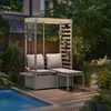 A garden sofa set with cushions and a canopy, situated on a wooden deck next to a swimming pool, surrounded by lush greenery. Náhled obrázku produktu
