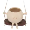 A ceramic planter shaped like a smiling character sitting on a swing. Anteprima dell’immagine prodotto