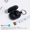 A pair of black wireless earbuds in their charging case, next to a measuring tape. Anteprima dell’immagine prodotto