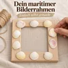Hände kleben Herzmuscheln auf einen Bilderrahmen aus Holz Produktbild-Vorschau