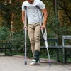 A man with a broken leg is walking with crutches in a park. Voir les images du produit